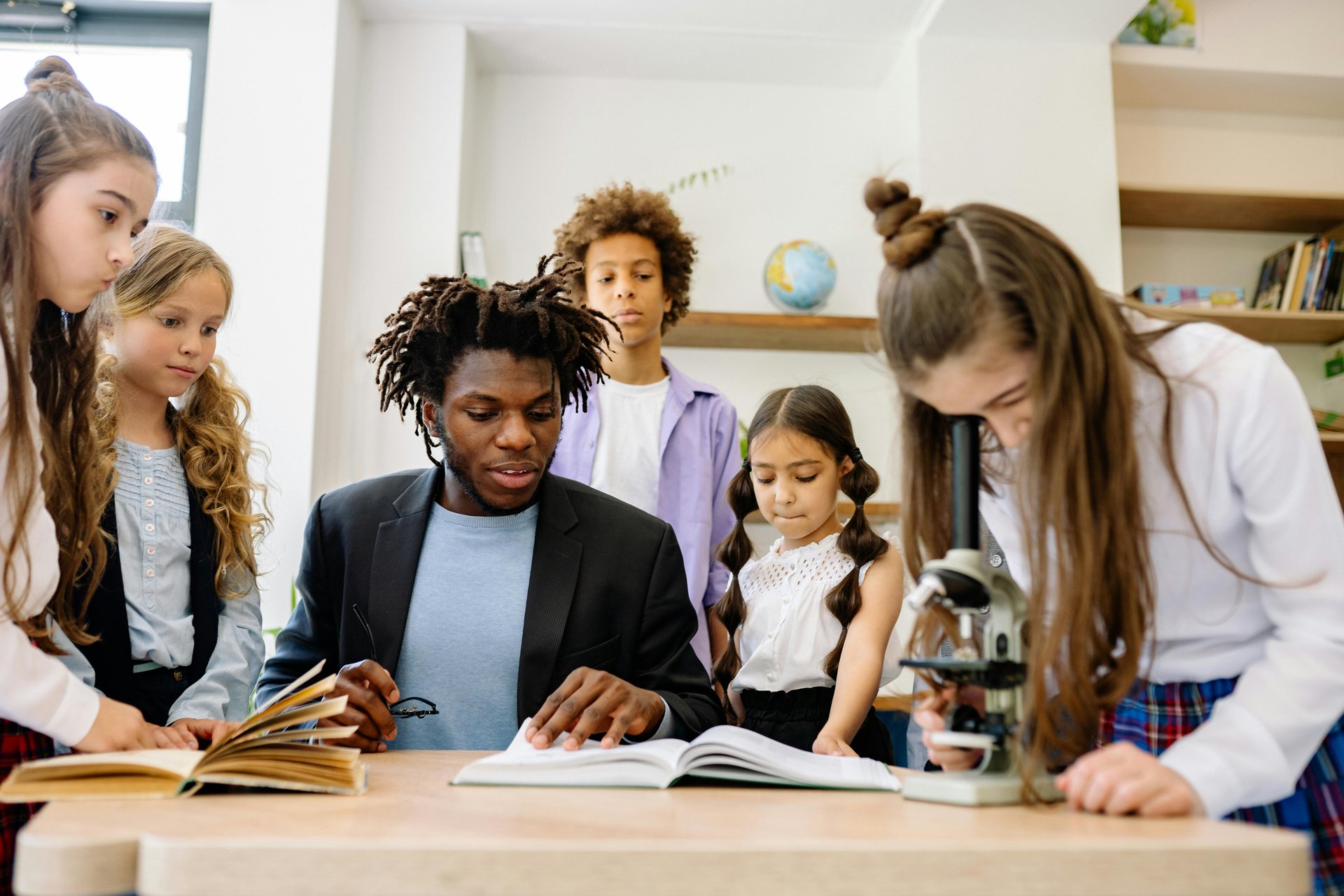Students gathered around a teacher reviewing a book