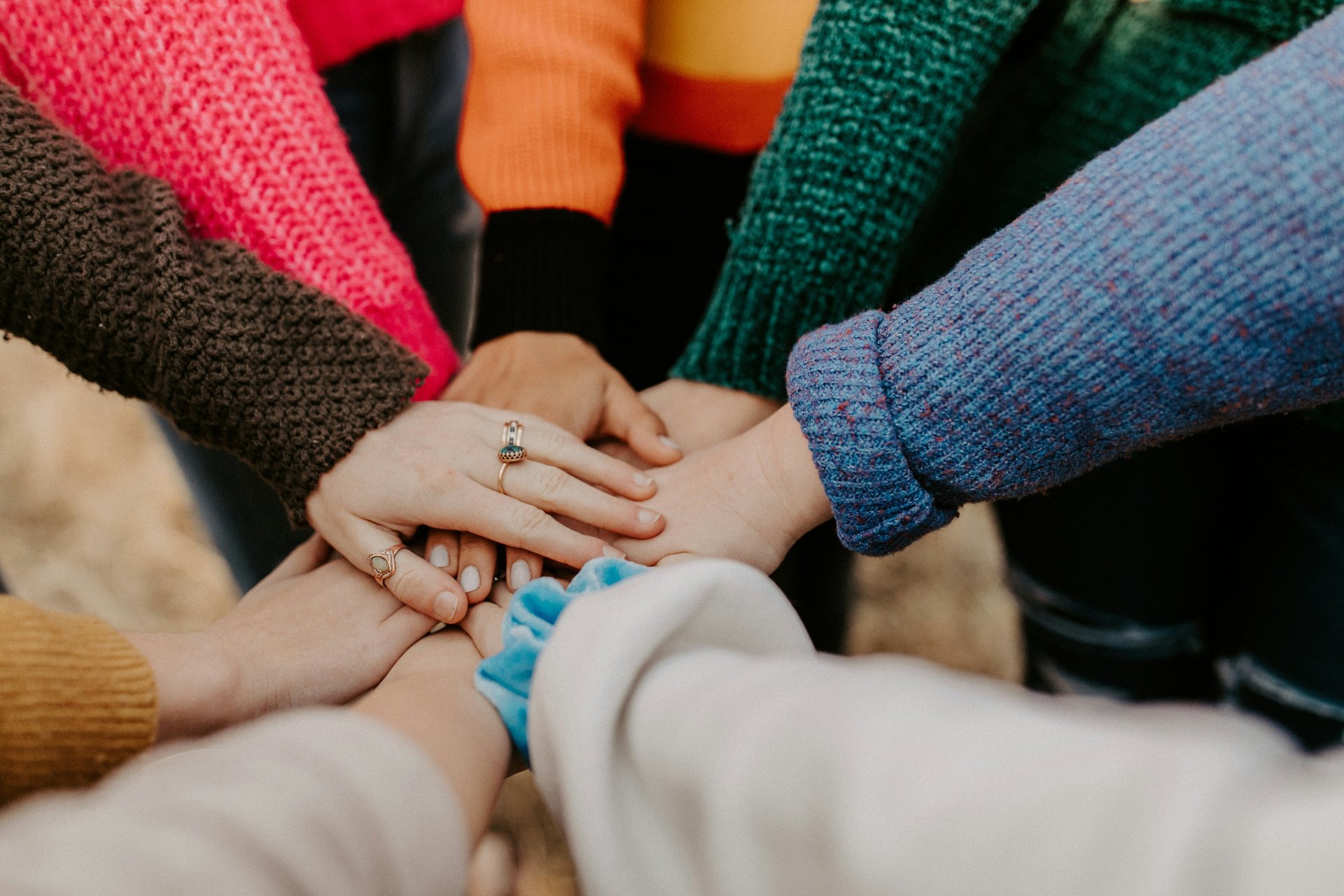 Students in a circle with hands together in collaboration